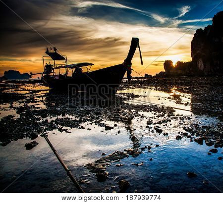 traditional long tail boat silhouette at low tide in sunset liights on Ton Sai beach, Thailand