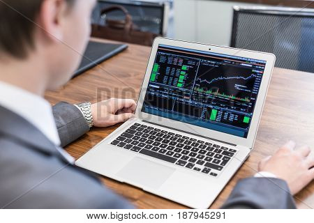 Corporate businessman analyzing economic data on laptop computer. Man's hands on notebook computer, business person at workplace.
