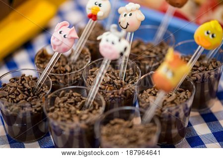 Brigadeiro (brazillian mix of chocolate and condensed milk) with animals decoration spoon in a small plastic glass