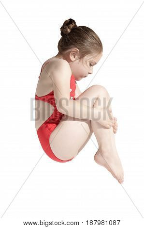 Little caucasian female diver (6 years old) jumping in diving pose  tucked his knees to his chin on white background.