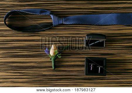 Wedding details. Groom accessories. Cufflinks tie and boutonniere on table.