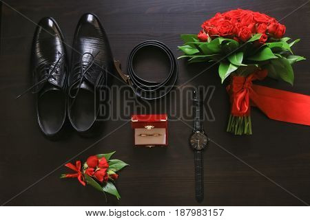 Wedding details. Groom accessories. Shoes rings belt boutonniere and watch on table