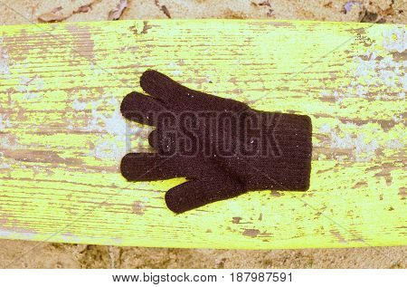 Lost Woolen Gloves On Yellow Bench. Sandy Gren Wooden Bench.  Sandbox With Dirty Sand In Kindergarde
