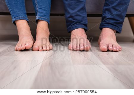 Close-up Of Couple's Feet On Floor
