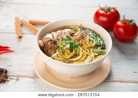 Asian soup noodles and chicken in bowl on wooden background. 