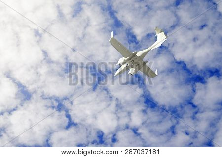 A Small Private White Plane With Screws Flies On The Background  Blue Sky With Clouds