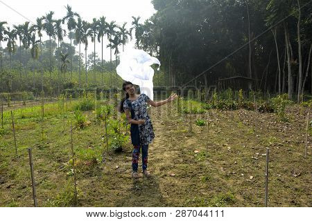 A Beautiful Girl Wearing Blue Color Salwar Kameez Flying Her Dupatta In Air In The Field On A Sunny 