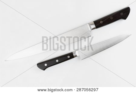 Two kitchen knives on light gray background shot from above