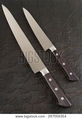 Two never used kitchen knives on black wooden board
