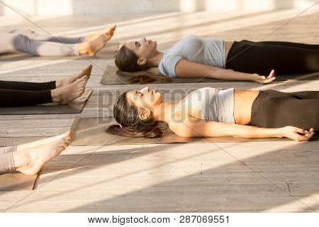 Group Of Attractive Women Practicing Yoga In Corpse Exercise