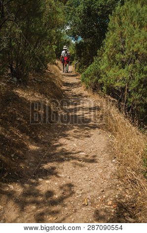 Monfrague Park, Spain - July 04, 2018. People Walking Along Dirt Path Amid Bushes And Trees On A Sun