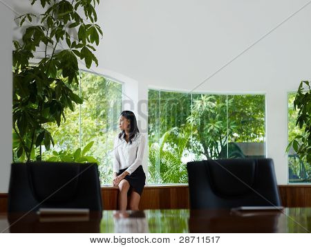 Businesswoman Contemplating Out Of Window In Meeting Room