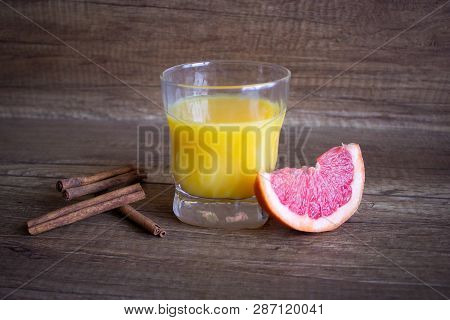 Orange Juice With Grapefruit. A Glass Of Grapefruit Juice On A Wooden Background. Cinnamon Cocktail