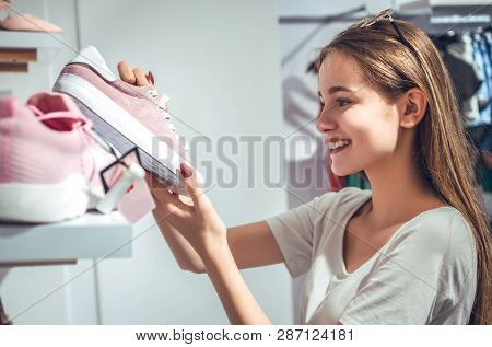 Нappy Young Woman Customer Choosing Pair Of Sneakers Shoes And Buying It In Clothes Store.casual Sho