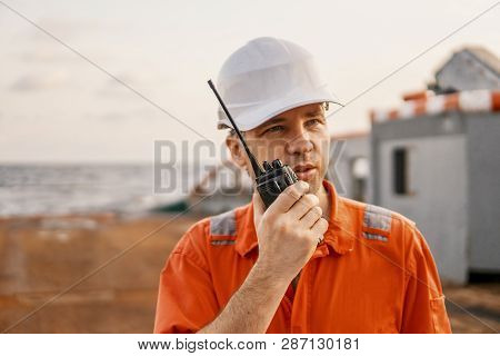 Deck Officer On Deck Of Offshore Vessel Holds Vhf Walkie-talkie Radio