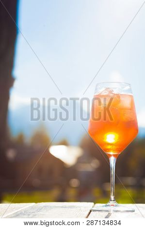 Glass Of Delicious Aperol Spritz Cocktail On Blurred Sunny Mountains Background