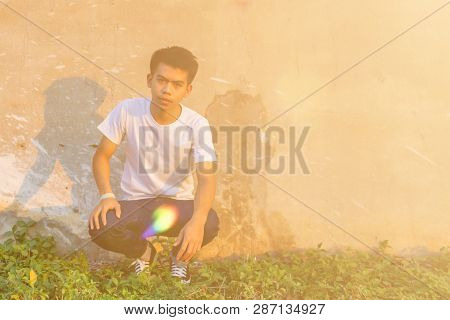 Photo Of A Young Thai Boy Is Standing Front Of The Dirty Wall In The White Shirt With Smilingly Happ