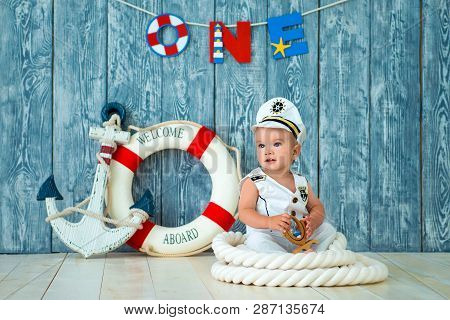 Photoshoot For A Boy Of One Year. Little Sea Captain, Sailor On Toy Ship With Steering Wheel. Sea An