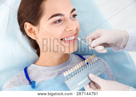 Dentist Selecting Patient's Teeth Color With Palette In Clinic