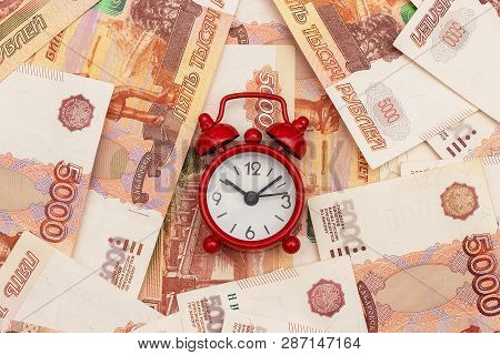 Red Alarm Clock On The Background Of Russian Five Thousandth Bills. Concept Time Is Money.