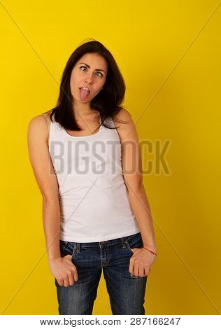 Pretty Girl With Dark Hair In Casual Clothes In Good Mood Makes A Wry Face And Makes A Face On A Bri