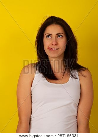 Pretty Girl With Dark Hair In Casual Clothes In Good Mood Makes A Wry Face And Makes A Face On A Bri