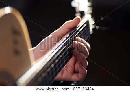 Under Bright Lighting, A Person Plays An Acoustic Guitar Melody, Holding The Hand Chords