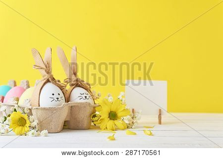 Easter Colored Eggs In Paper Tray With Decorationd On Yellow Background