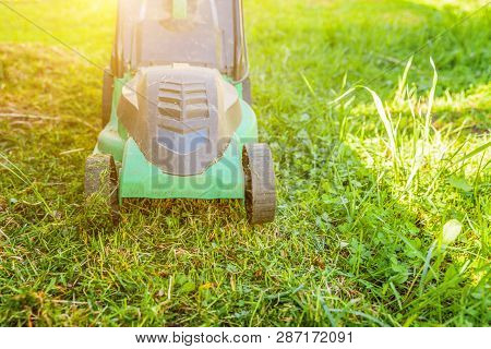 Lawn Mower Cutting Green Grass In Backyard In Sunny Day. Gardening Country Lifestyle Background. Bea