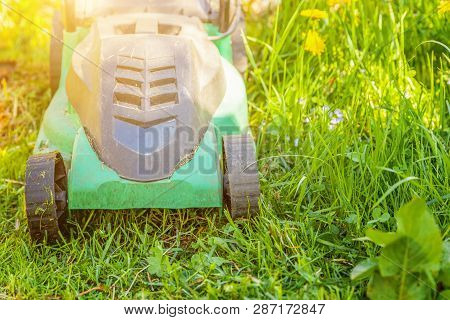 Lawn Mower Cutting Green Grass In Backyard In Sunny Day. Gardening Country Lifestyle Background. Bea