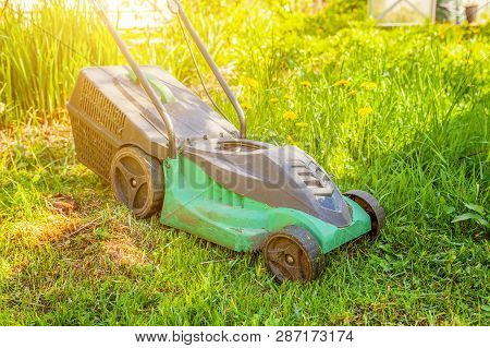 Lawn Mower Cutting Green Grass In Backyard In Sunny Day. Gardening Country Lifestyle Background. Bea