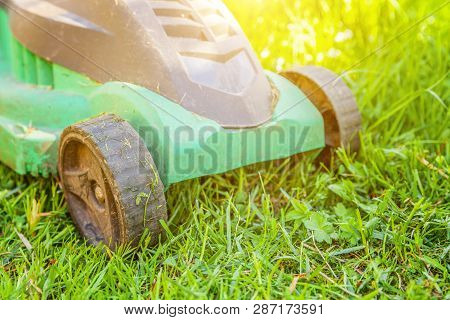Lawn Mower Cutting Green Grass In Backyard In Sunny Day. Gardening Country Lifestyle Background. Bea
