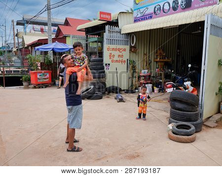 Cambodia, Siem Reap 12/08/2018 A Man With A Child In His Arms Near The Tire Shop, Slums Of Asia, Res