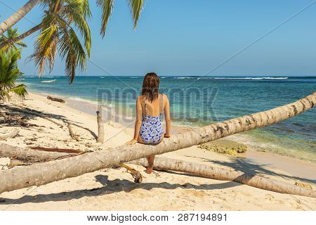 Woman Sitting On Palm Tree On The Beach. Healthy People Lifestyle. Woman Relaxing On The Beach. .vac