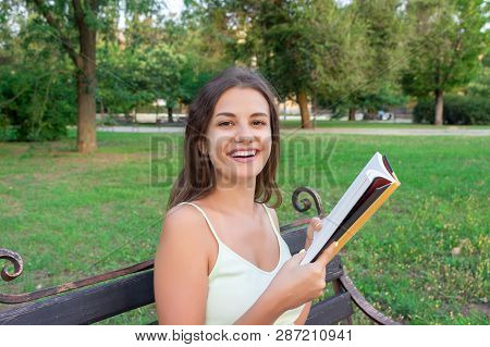 Beautiful Young Brownhair Girl Is Reading The Book And Enjoys The Smell Of A Fresh Printed Book Sitt