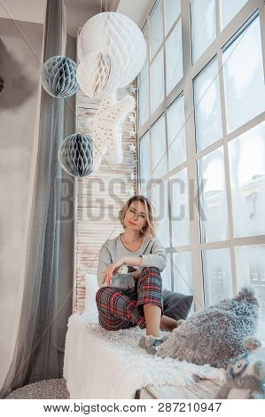 Beautiful Girl Sitting Near A Large Window.