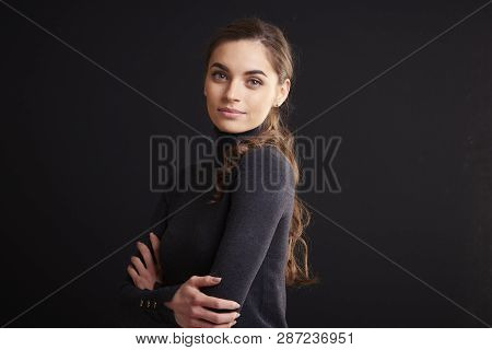 Attractive Young Woman Studio Portrait While Standing At Dark Background