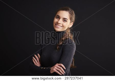 Attractive Young Woman Studio Portrait While Standing At Dark Background