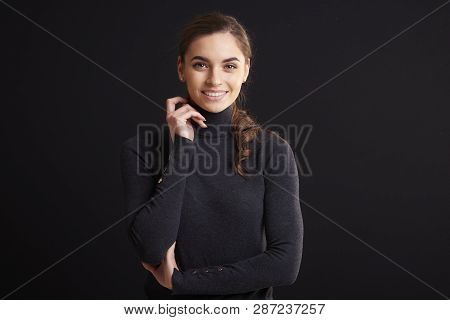 Attractive Young Woman Studio Portrait While Standing At Dark Background