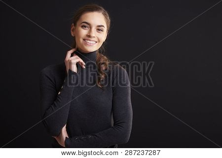 Attractive Young Woman Studio Portrait While Standing At Dark Background