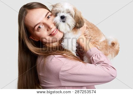 Headshot Of Attractive Female Holds Pedigree Dog Near Face, Demonstrates Trughtful Feelins, Love And