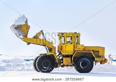 Novyy Urengoy, Russia - April 6, 2013: Yellow Front-end Loader Loads A Snow In A Truck In The City S