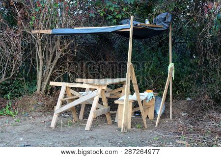 Makeshift Improvised Table And Bench With Small Roof Made Of Cerade In Front Of Dense Trees Surround