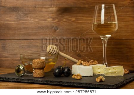 Chopped Camembert Cheese, Nuts, Honey, Sweet Grapes And Cork From Wine Bottle On The Background Of A