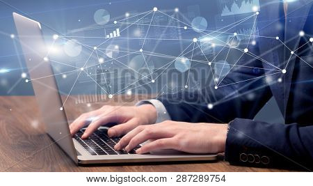 Businessman typing on laptop with linked reports charts grapghs around