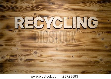 RECYCLING word made with building blocks on wooden board