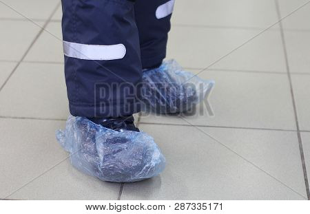 Feet In Blue Shoe Covers. In The Photo Are Two Children Feet In Shoe Covers. The Floor Is Clean. Com