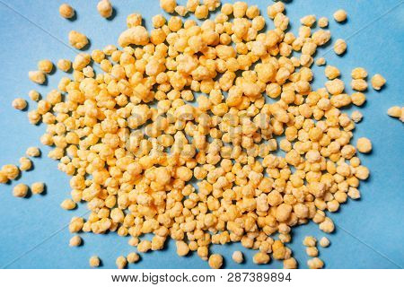 Yellow Granules On A Blue Background. Candies