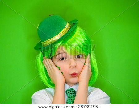 A Dreaming Cute Boy Is Holding His Head On His Hands Celebrating St. Patricks Day. A Small Child In 