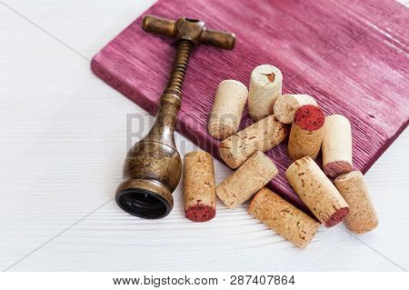 Vintage Corkscrew And Heap Used Wine Corks On  Wooden Background. Spin And Stopper Corks From Red Wi